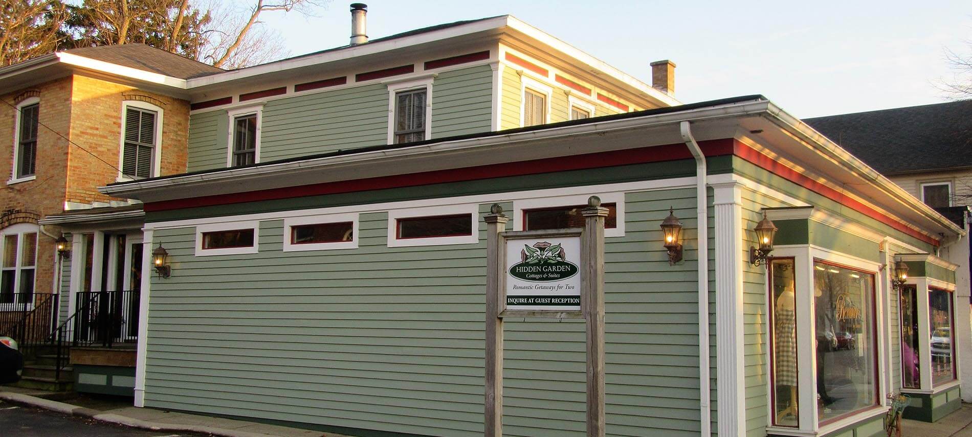 Outside of Hidden Gardens parking. Green building with small rectangle windows.