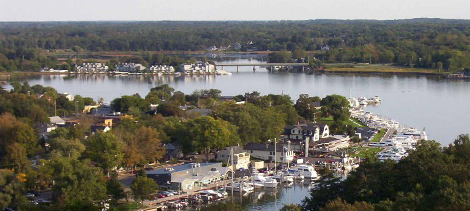 Bay with house boats and entrance to open water and lots of green trees.