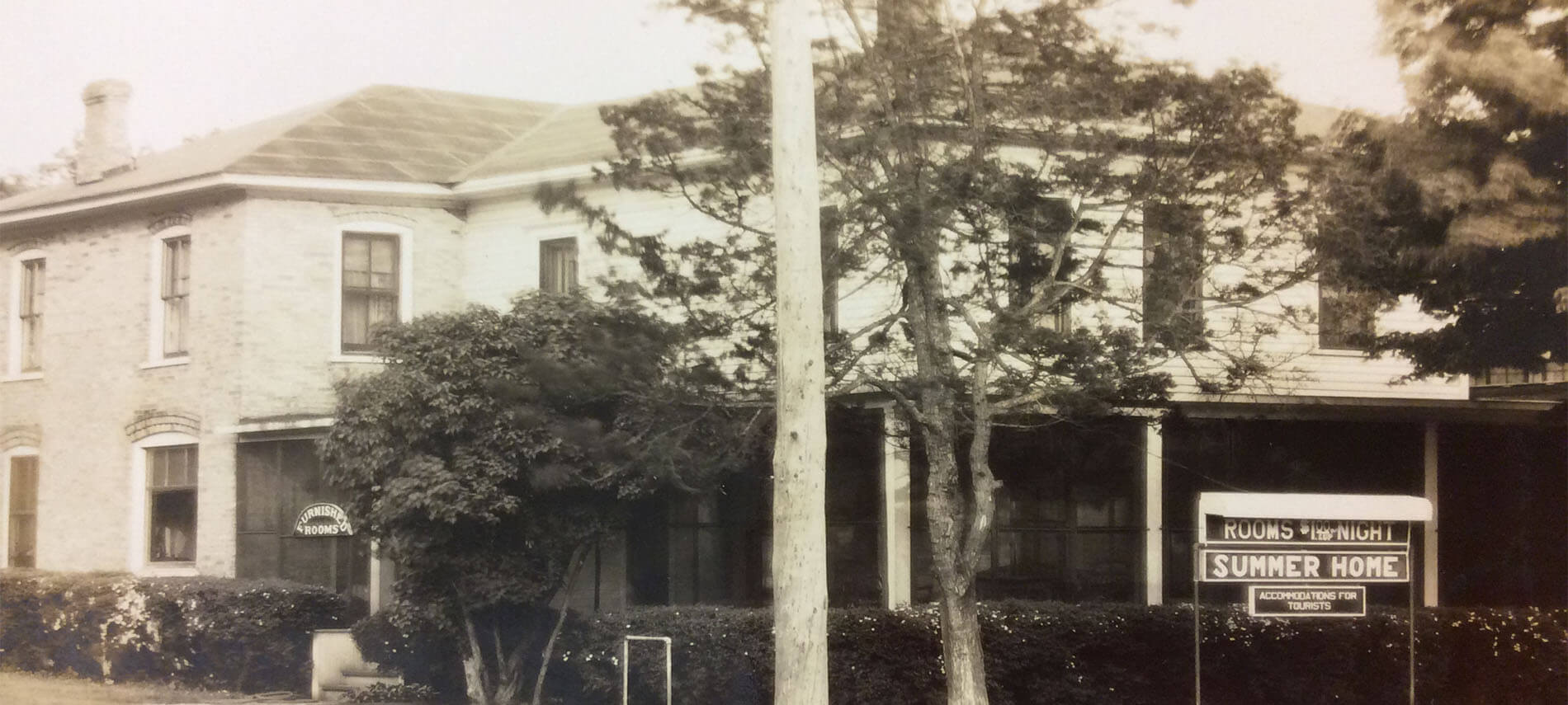 Old photo of hotel or bed and breakfast with sign for rooms. Name on sign is Summer Home.