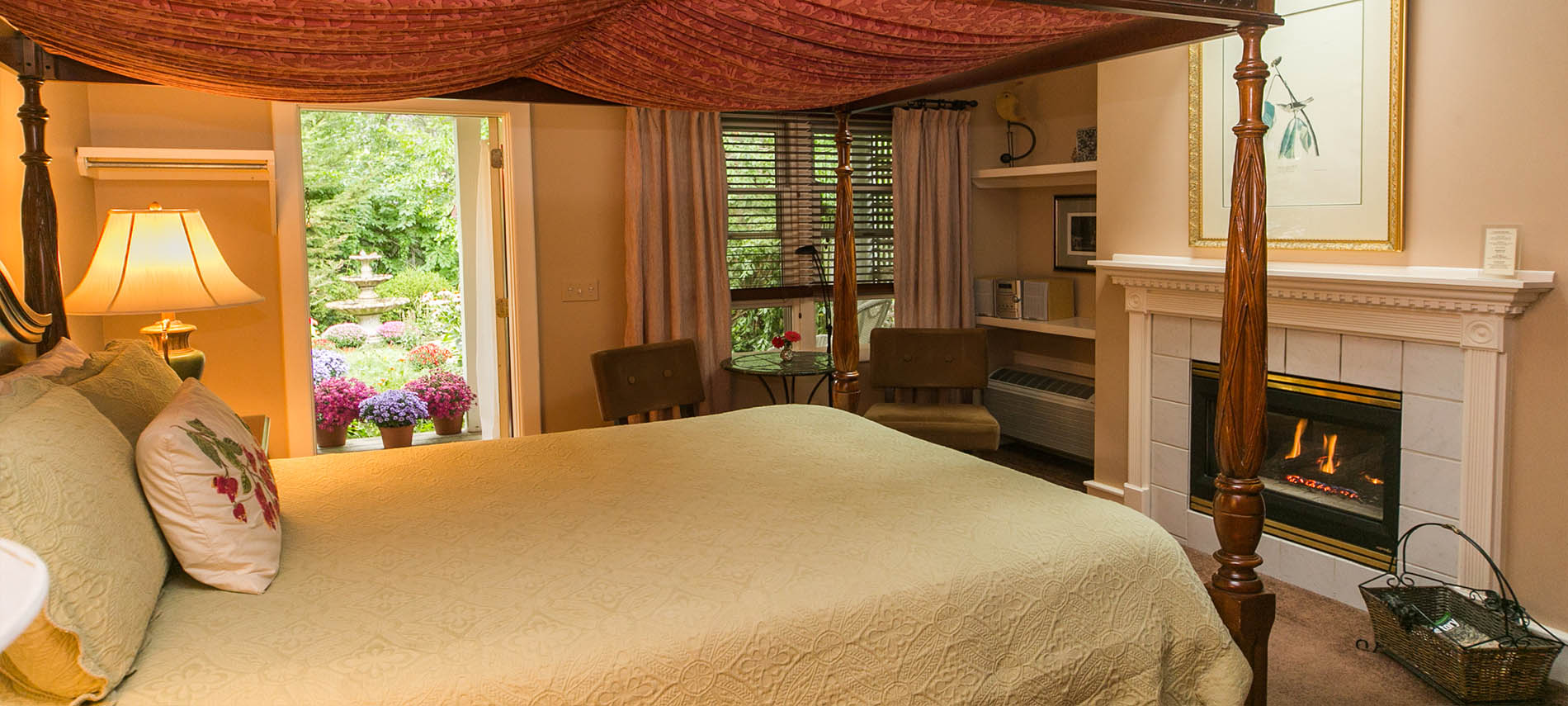 Four post bed with canopyin foreground and sitting area in far corner offering view through open windows.