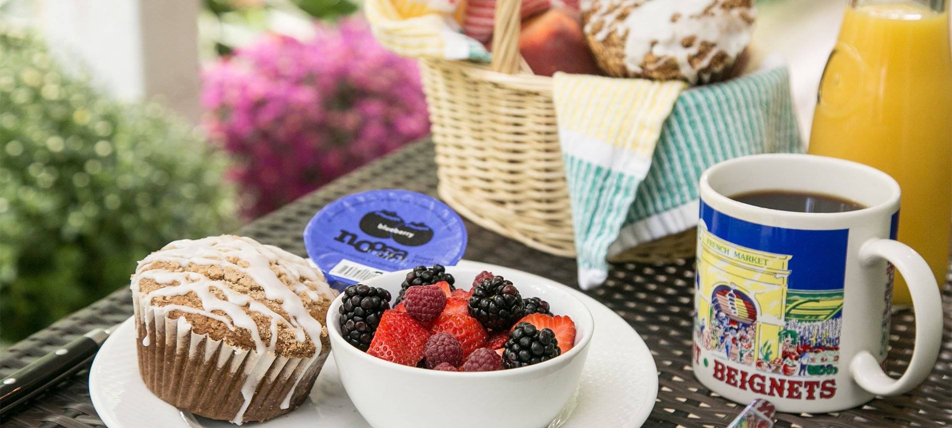 mixed berries with muffin, coffee, orange juice and bread basket.